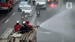 Petugas pemadam kebakaran (Damkar) melakukan penyemprotan cairan disinfektan di sepanjang jalan Thamrin-Sudirman, Jakarta, Sabtu (28/3/2020). Penyemprotan menggunakan mobil pemadam kebakaran tersebut bertujuan untuk mengantisipasi penyebaran Virus Corona (COVID-19). (merdeka.com/Imam Buhori)