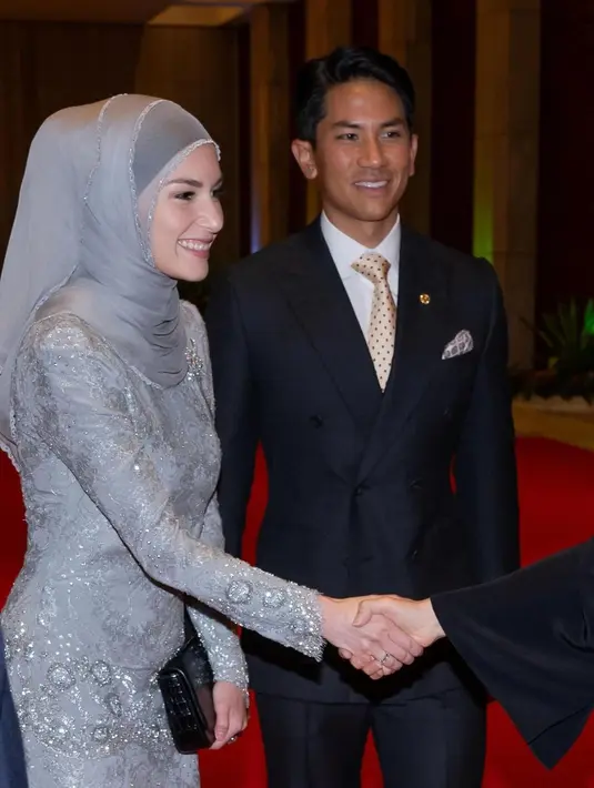 Ia terlihat mengenakan baju kurung warna abu-abu dengan detail full lace rancangan desainer yang sama saat ia menikah. Baju kurung tersebut ia padukan dengan hijab warna senada. [@tehfirdaus]