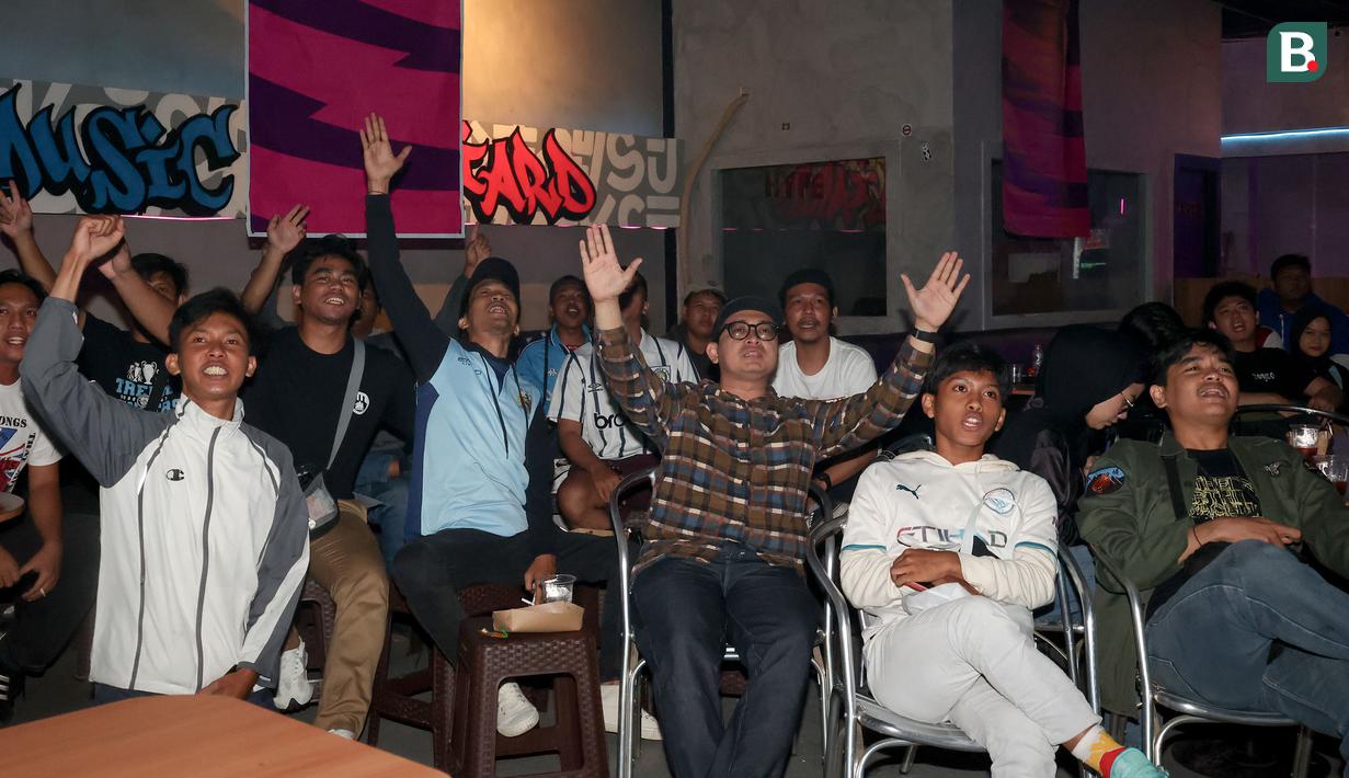 Anggota komunitas Manchester City Supporters Club Indonesia bersorak saat tim kesayangannya hampir mencetak gol dalam acara Roaring Night Liga Inggris 2023/2024 antara Manchester City melawan Arsenal di Hype Cafe, Depok, Minggu (31/3/2024) malam. (Bola.com/Abdul Aziz)