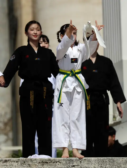 Atlet Taekwondo dari Korea Selatan melepaskan burung merpati usai tampil di depan Paus Fransiskus saat pertemuan umum mingguan di Lapangan Santo Petrus, Vatikan (30/5). (AP Photo/Gregorio Borgia)