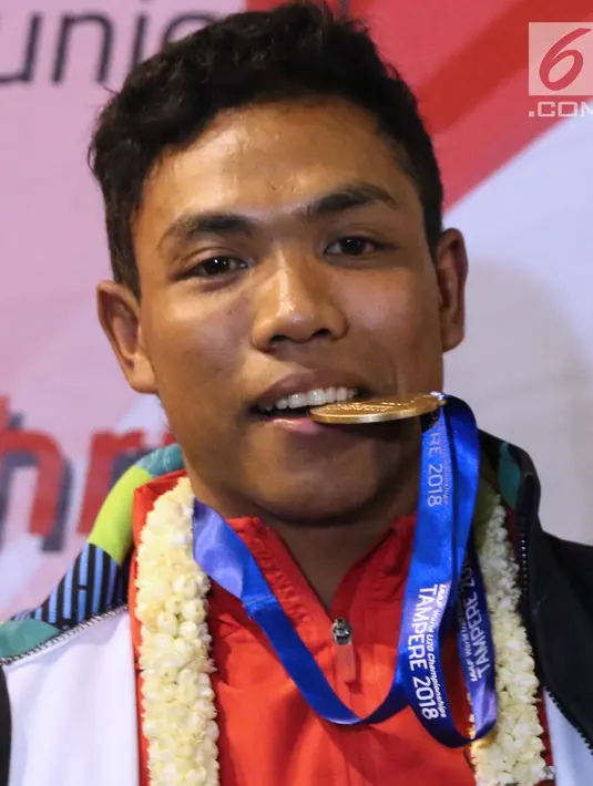 Pelari muda Indonesia, Lalu Muhammad Zohri menggigit medali emas saat upacara penyambutan di Terminal 3 Bandara Soetta, Tangerang, Selasa (17/7/2018). Lalu M Zohri meraih emas lari 100m putra di Kejuaraan Dunia Atletik U-20. (Liputan6.com/Helmi Fithriansyah)