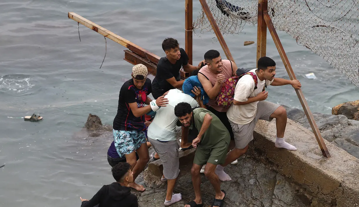 Imigran  berkumpul di sepanjang pagar di lokasi bentrokan dekat Fnideq, di perbatasan Maroko-Spanyol, Jumat, 31 Juli 2026. (AFP/  Abdel Majid Bziouat)