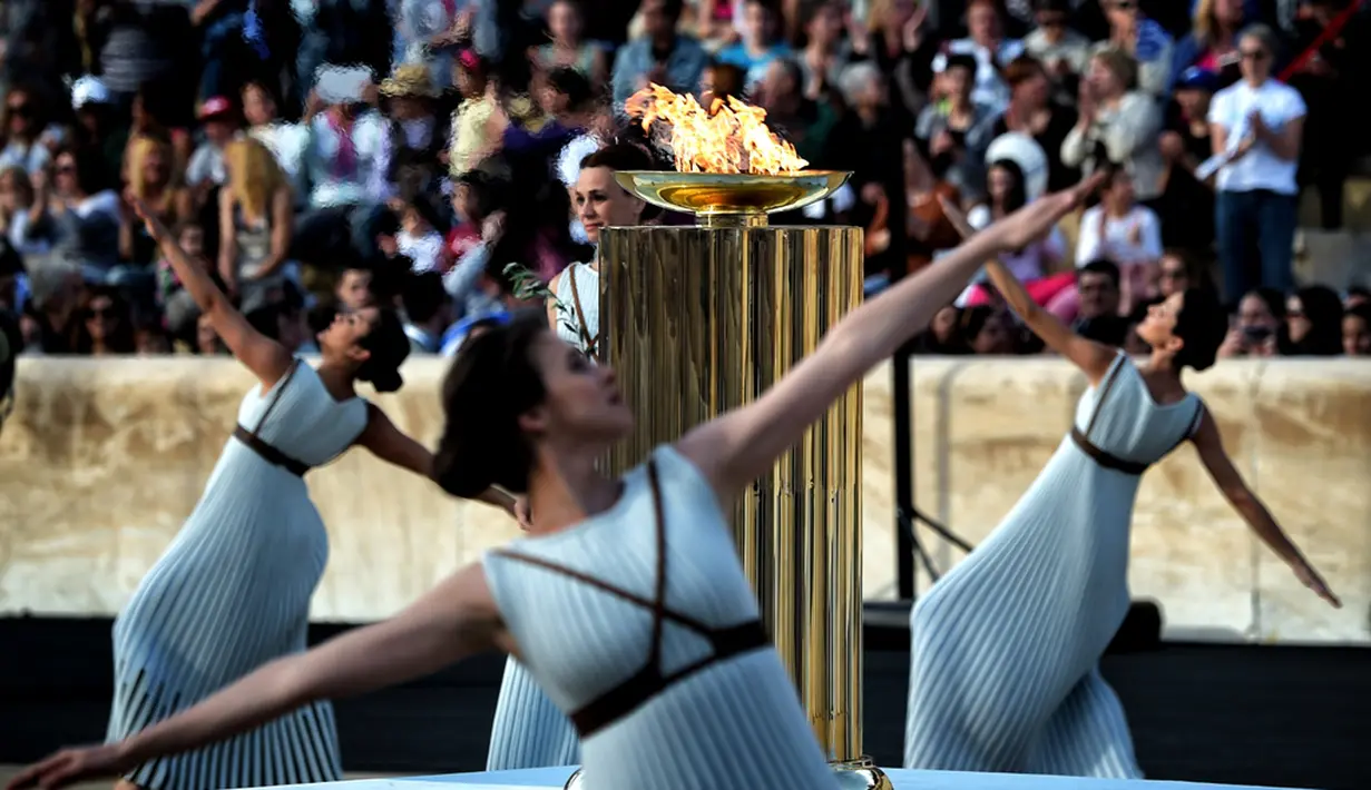 Para penari beraksi di sekitar koldron api olimpiade dalam sebuah upacara penyerahan kepada panitia Olimpiade Rio di Stadion Panathinean, Athena, Yunani, (27/4/2016). (AFP/Aris Messinis)