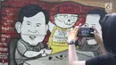 Warga mengabadikan mural Capres Joko Widodo dan Prabowo Subianto di Jalan Juanda, Depok, Jabar, (21/11). Mural tersebut memiliki pesan agar masyarakat tetap damai dan berteman meski berbeda memilih capres di Pilpres 2019. (Liputan6.com/Herman Zakharia)
