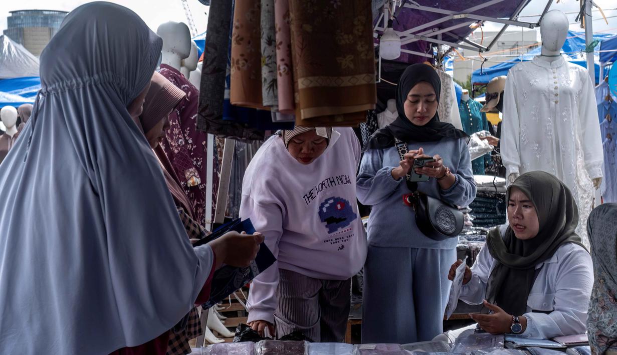 Pembeli berjalan di antara kios-kios penjual pakaian lokal di salah satu pasar tradisional, Jakarta, Kamis 20 November 2025. Sempat mengalami guncangan akibat maraknya produk impor dengan harga yang sangat murah, industri tekstil nasional mendapat titik terang. (BAY ISMOYO/AFP)