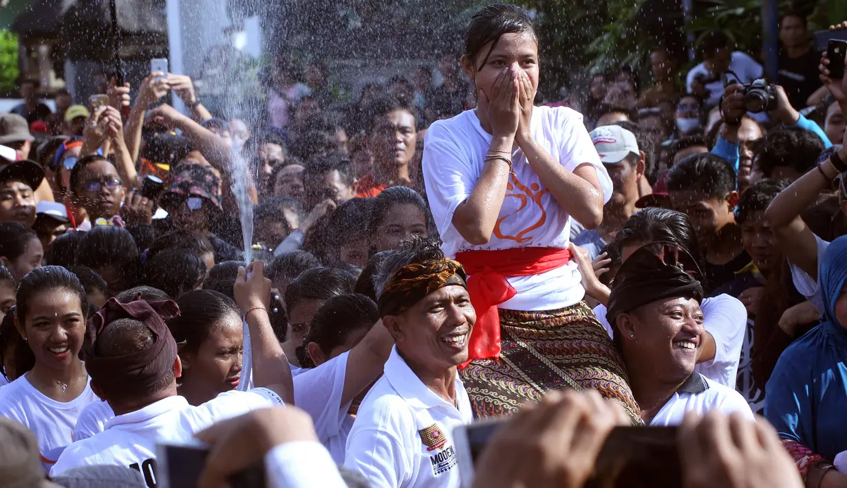 Remaja wanita digendong sebelum dipeluk oleh pasangan prianya saat festival Omed-omedan di Bali, Kamis (29/3). Festival yang dilakukan sehari setelah Hari Raya Nyepi itudigelar untuk memupuk persaudaraan pemuda dan pemudi desa. (AP Photo/Firdia Lisnawati)