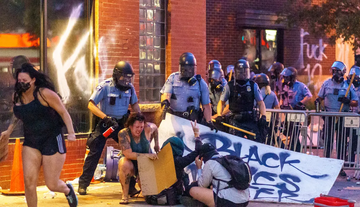 Polisi menyemprot demonstran dengan merica saat unjuk rasa atas kematian George Floyd oleh polisi di luar Third Police Precinct, Minneapolis, Minnesota, Amerika Serikat, Rabu (27/5/2020). Ribuan warga kulit hitam turun ke jalan menuntut polisi mengusut tuntas kasus tersebut. (Kerem Yucel/AFP)