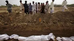 Sejumlah warga melihat proses pemakaman massal korban tewas akibat gelombang panas di Karachi, Pakistan, Jumat (26/6/2015). Lebih dari 1.150 orang tewas akibat gelombang panas. (REUTERS/Akhtar Soomro)