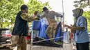 11 orang ditangkap dan dinyatakan sebagai tersangka dalam kasus ini. Tampak dalam foto, para petugas dari lembaga konservasi satwa liar membawa sangkar berisi kadal layar atau naga layar yang disita dari para tersangka penyelundupan hewan yang dilindungi di Markas Besar Kepolisian Daerah Jawa Timur di Surabaya pada Rabu 15 April 2026. (JUNI KRISWANTO/AFP)