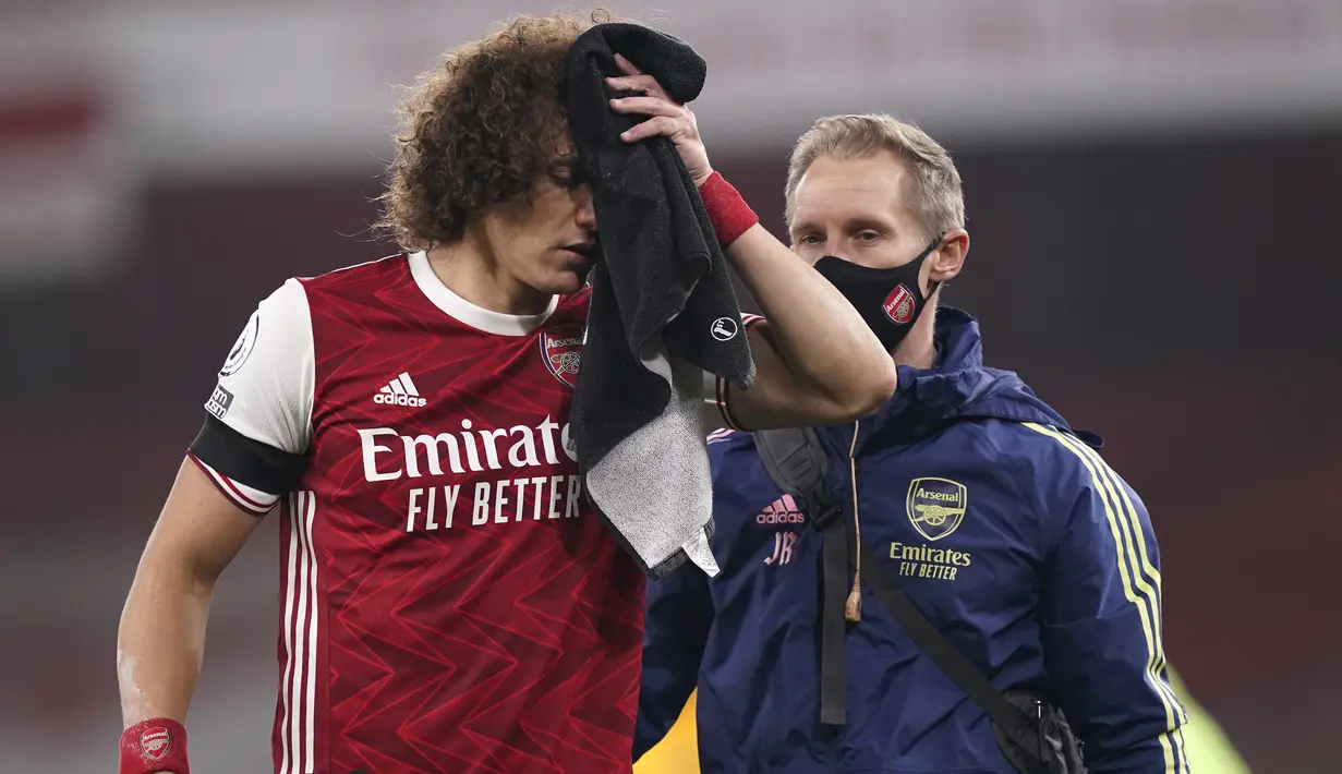 Bek Arsenal, David Luiz memegang handuk pada luka di kepalanya setelah terlibat benturan dengan Raul Jimenez dari Wolverhampton Wanderers pada pekan kesepuluh Liga Inggris di Emirates Stadium, London, Minggu (29/11/2020). Arsenal takluk 1-2 dari Wolverhampton Wanderers. (John Walton/Pool via AP)