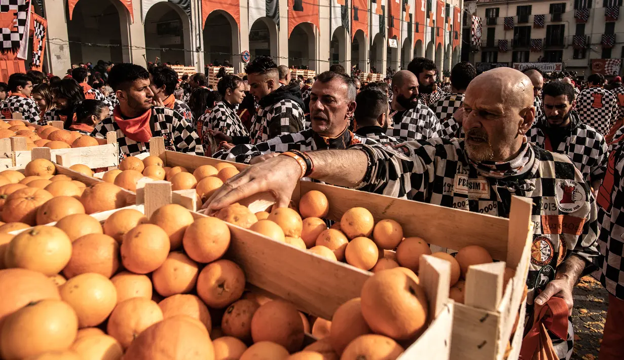 Peserta mengambil jeruk untuk mengikuti tradisi "perang jeruk" selama Karnaval Ivrea di Turin, Italia, Minggu (3/3). Perang Jeruk ini biasa dilaksanakan di bulan Februari setiap tahunnya selama tiga hari (MARCO BERTORELLO/AFP)