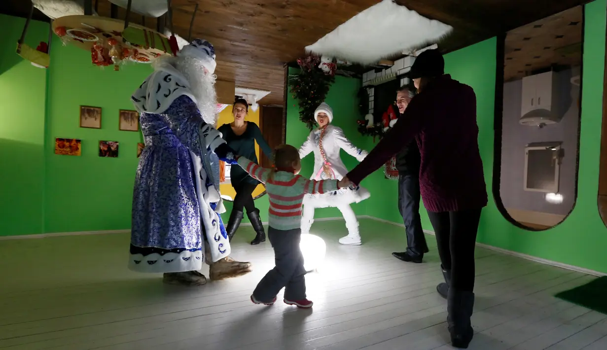 Ded Moroz atau Santa Claus dari Rusia menari bersama para pengunjung saat merayakan Natal di rumah terbalik Royev Ruchey Park, Krasnoyarsk, Rusia (7/12). Rumah terbalik ini dibangun untuk menarik wisatawan. (Reuters/Ilya Naymushin)