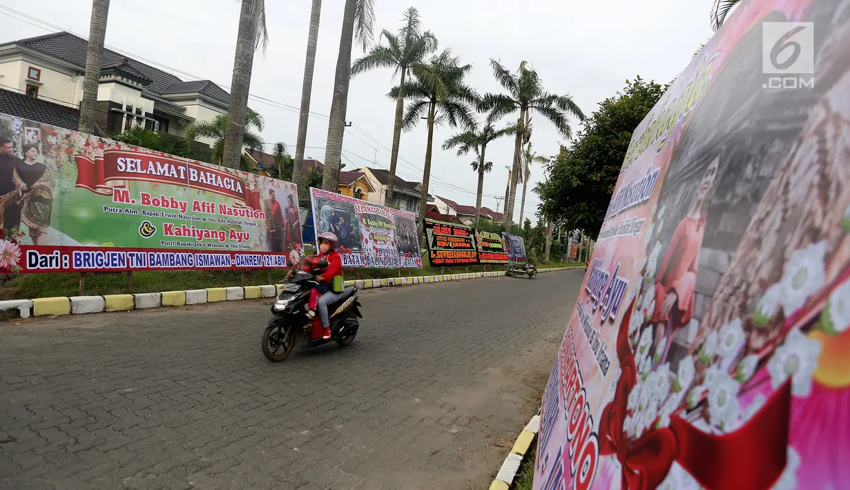 Warga melintas di depan karangan bunga dan ucapan selamat untuk Kahiyang-Bobby yang terpampang di pinggir jalan Komplek Bukit Hijau Regency (BHR), Medan, Kamis (23/11). (Liputan6.com/JohanTallo)