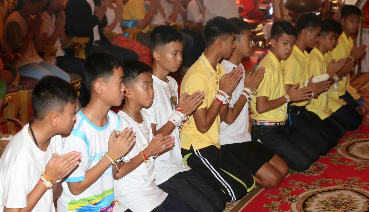 Pelatih tim sepak bola remaja Thailand, Ekkapol Janthawong (empat kanan) bersama 12 anak asuhnya mengikuti ritual setelah berhasil selamat dari dalam gua,  Distrik Mae Sai, Chiang Rai, Kamis (19/7). (AP Photo/Sakchai Lalit)