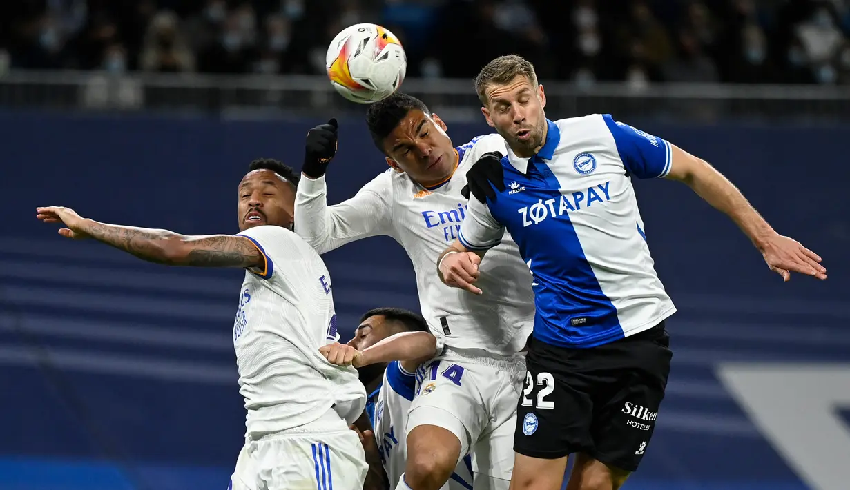 Bek Deportivo Alaves Florian Lejeune (kanan) bersaing dengan pemain Real Madrid Eder Militao (kiri) dan Casemiro (tengah) pada pekan ke-25 La Liga Spanyol di Santiago Bernabeu, Minggu (20/2/2022) dinihari WIB. Real Madrid menang meyakinkan dengan skor 3-0. (OSCAR DEL POZO / AFP)