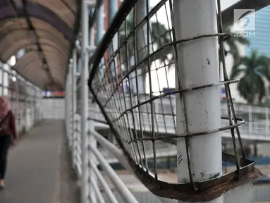 Pejalan kaki saat melewati jembatan penyeberangan orang (JPO) yang berada di Jalan Sudirman, Jakarta, Rabu (17/4). JPO yang berada di tengah gedung-gedung perkantoran ini tidak terlihat terurus dan usang. (Merdeka.com/Iqbal Nugroho)