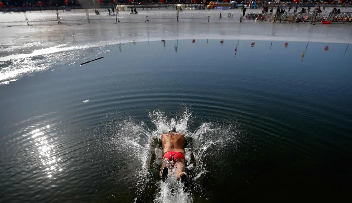 Seorang pria menyelam ke air setengah beku di Danau Shichahai di Beijing, China (24/1). Menurut beberapa penduduk setempat, berenang di air dingin baik untuk kesehatan. (AP Photo / Andy Wong)