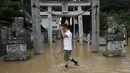 Salah satu warga melintas di depan gerbang sebuah kuil yang ikut terendam akibat bencana tanah longsor di wilayah perumahan di Asaminami, Hiroshima, Jepang, (20/8/2014). (REUTERS/Toru Hanai)