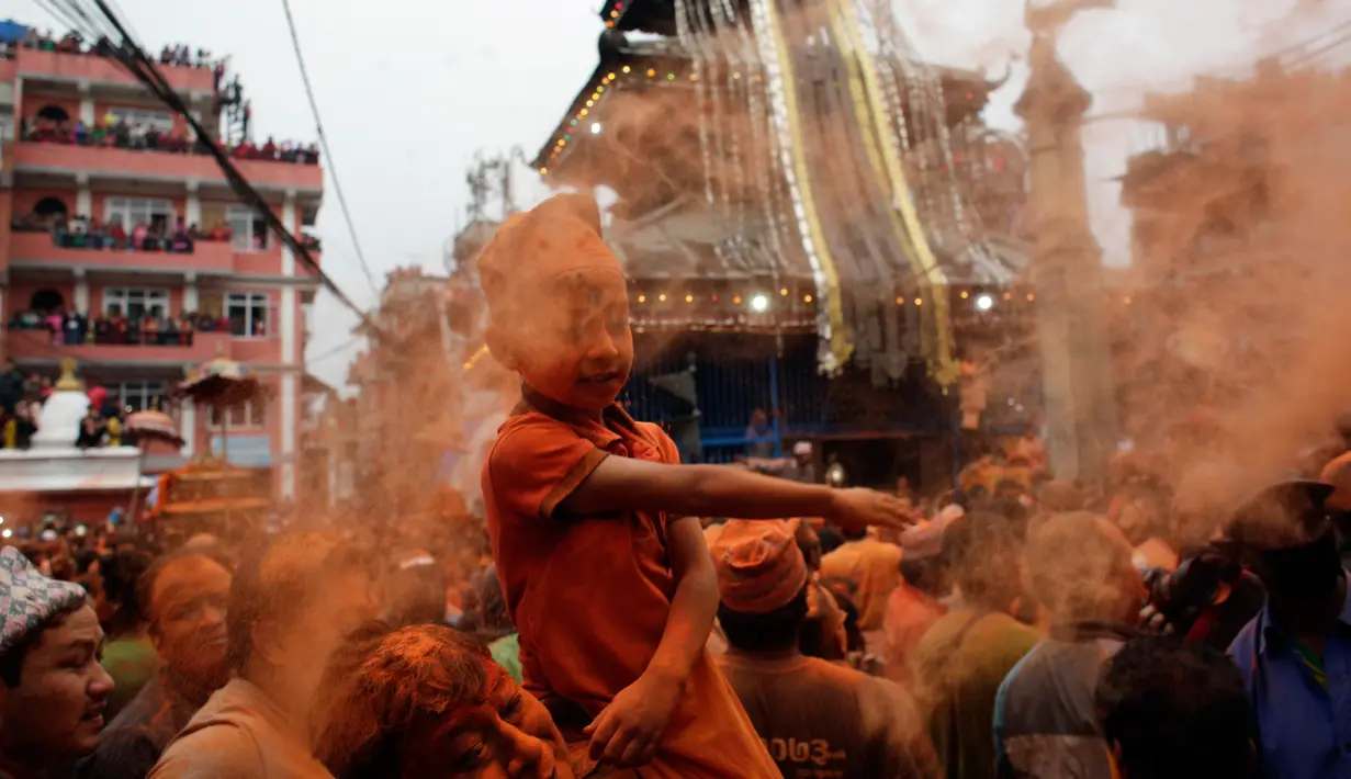 Seorang anak menaburkan bubuk vermillion saat perayaan sindoor Jatra festival di Bhaktapur, Nepal (15/4). Perayaan ini untuk menyambut datangnya musim semi dan Tahun Baru. (AP Photo/Niranjan Shrestha)
