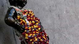 Gambar pada 12 Agustus 2019 memperlihatkan patung 'Manneken Pis' dalam balutan baju bermotif bunga di ibu kota Belgia, Brussels, Senin (12/8/2019). Patung perunggu yang hanya berukuran 60 sentimeter ini berwujud bocah lelaki yang sedang buang air kecil. (Photo by Kenzo TRIBOUILLARD / AFP)