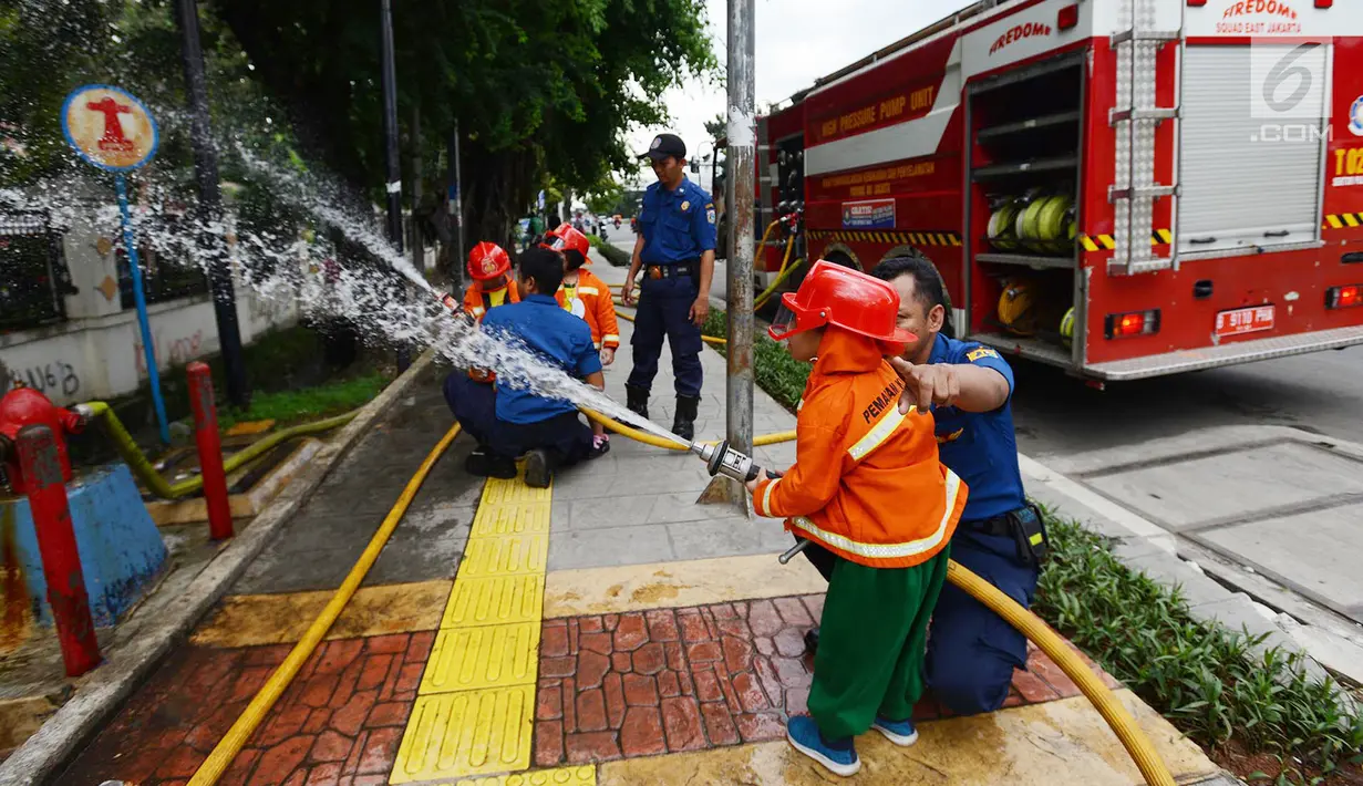 Petugas pemadam kebakaran mengajari anak-anak TK cara memadamkan api di Jakarta, Kamis (21/3). Kegiatan ini bertujuan mengenalkan profesi pemadam kebakaran dan memberi pengetahuan proses pemadaman api kepada anak usia dini. (merdeka.com/Imam Buhori)