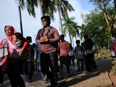 Pengunjung berjalan di kawasan Monumen Nasional, Jakarta, Senin (25/12). Libur perayaan Natal dimanfaatkan warga untuk berwisata di kawasan Monumen Nasional. (Liputan6.com/Helmi Fithriansyah)