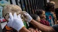 Seorang anggota keluarga sedang kenakan kacamata untuk jenazah kerabat yang diawetkan selama ritual adat yang disebut "Manene" di Panggala, Toraja Utara, (28/08/2020). (AFP/Hariandi Hafiz)