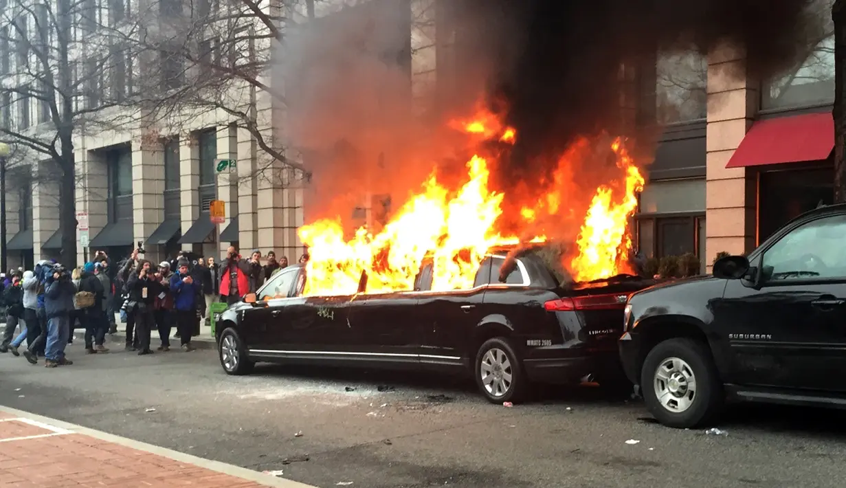 Sebuah mobil limusin dibakar oleh para pengunjuk rasa saat terpakir selama protes pelantikan Presiden Donald Trump di Washington, DC, AS, (20/1). Mobil mewah tersebut menjadi bulan-bulanan massa anti-Trump. (AP Photo/Juliet Linderman)