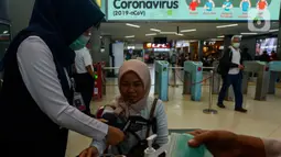 Seorang pengguna KRL menjalani pemeriksaan kesehatan di Stasiun Sudirman, Jakarta, Selasa (4/2/2020). PT Kereta Commuter Indonesia (KCI) melakukan sosialisasi tentang pencegahan penyebaran virus corona sambil membagikan masker secara gratis kepada penumpang. (merdeka.com/Imam Buhori)