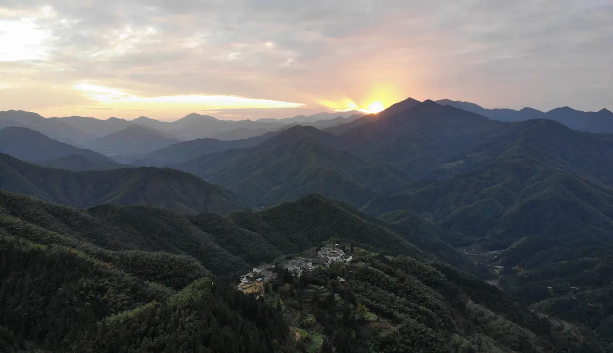 Foto dari udara yang diabadikan pada 4 November 2020 ini menunjukkan pemandangan saat senja di Desa Mulihong di wilayah Xiuning, Provinsi Anhui, China timur. Terletak di perbukitan yang menghadap tebing di tiga sisinya, desa itu dikenal sebagai "desa di atas awan". (Xinhua/Huang Bohan)