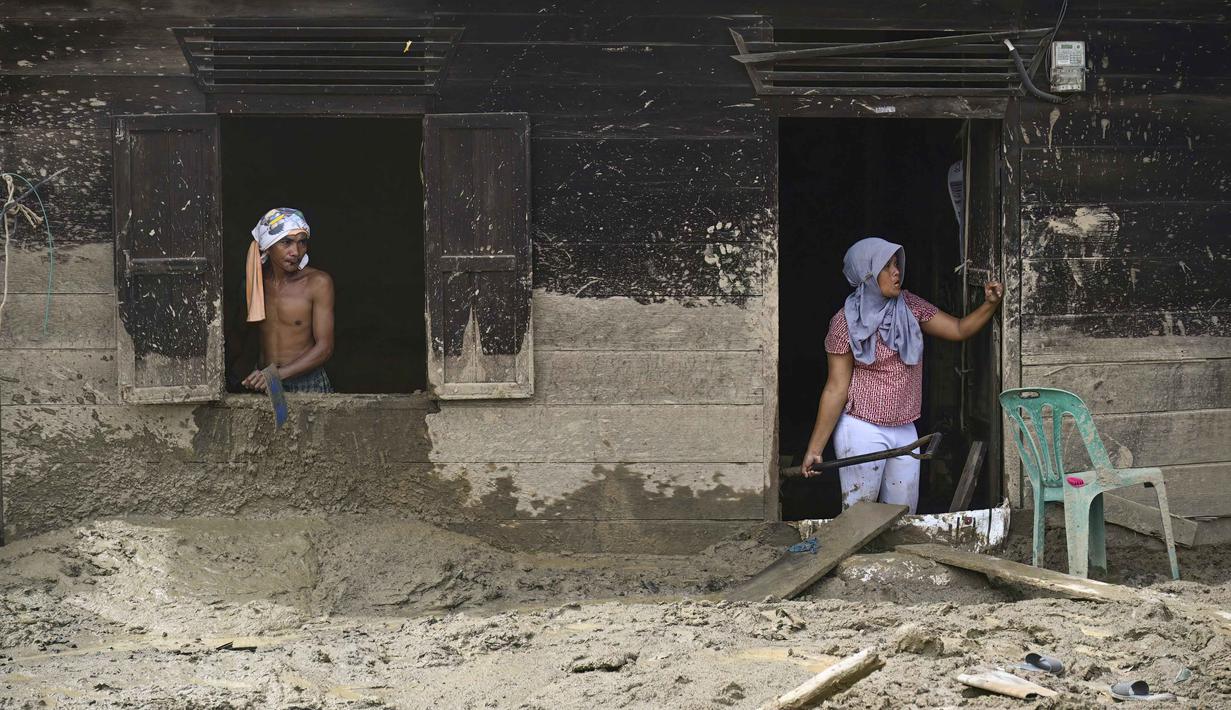 Tim gabungan berupaya mempercepat pembersihan material sisa bencana banjir bandang untuk memulihkan fungsi lingkungan dan akses publik. Tampak dalam foto, dua warga desa membersihkan rumah mereka yang rusak akibat banjir bandang di Desa Aek Garoga, Tapanuli Selatan, Sumatera Utara, pada Sabtu 27 Desember 2025. (YT Hariono /AFP)