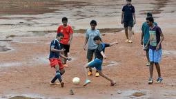 Anak-anak sekolah India bermain bola dekat genangan air di Bangalore, India, Rabu (11/11/2015) WIB.  (AFP Photo/Manjunath Kiran)