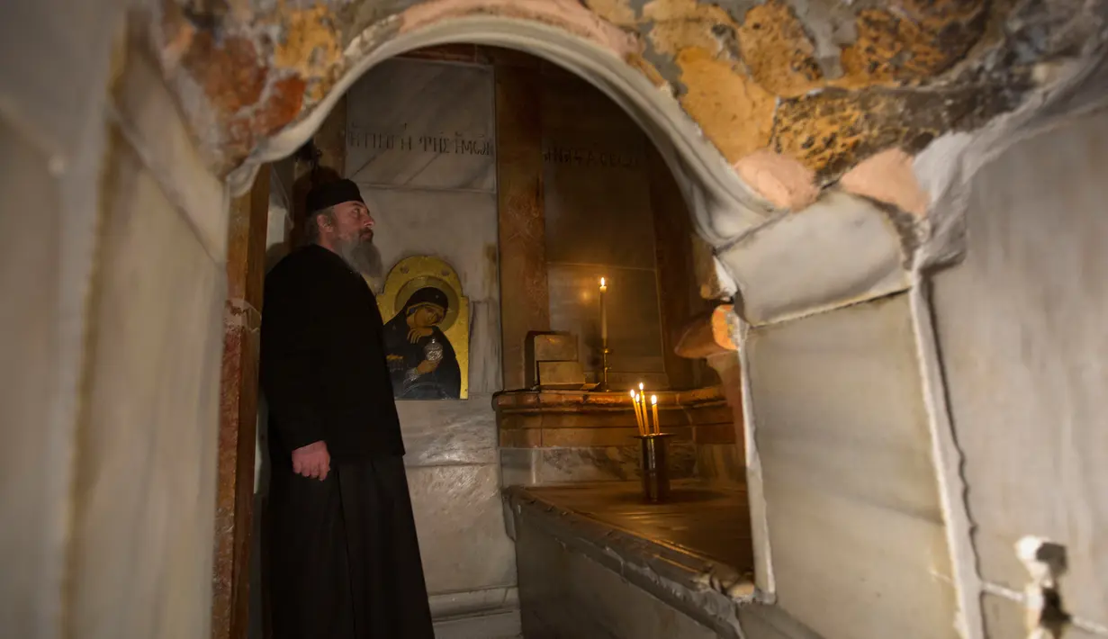 Seorang imam Yunani berdiri didalam Edicule yang sedang dalam tahap renovasi di Gereja Makam Kudus di Yerusalem (20/3). Gereja tersebut merupakan salah satu yang tertua, dibangun pada 325 M oleh Kaisar Konstantin dari Romawi. (AP Photo/Sebastian Scheiner)
