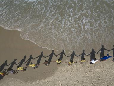 Orang-orang membuat barisan berpegangan tangan di sepanjang pantai Sao Conrado untuk berpelukan secara simbolis dengan laut pada Hari Laut Sedunia di Rio de Janeiro, Brasil, Kamis, 8 Juni 2023. (AP Photo/Bruna Prado)