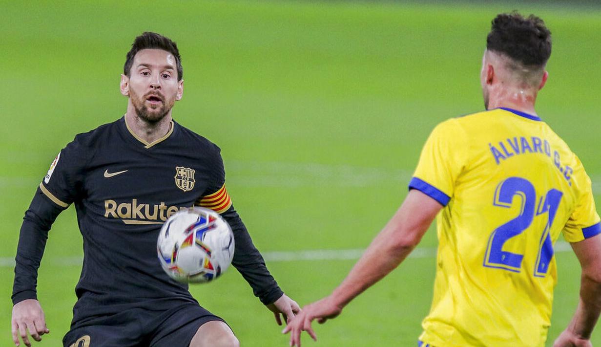 Striker Barcelona, Lionel Messi, berebut bola dengan pemain Cadiz, Alvaro Gimenez, pada laga Liga Spanyol di Stadion Ramon Carranza, Minggu (6/12/2020). Barcelona takluk dengan skor 1-2. (AP/Alvaro Rivero)
