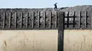 Seorang kolektor besi tua berlari di atas tumpukan besi setelah melompat untuk mencari besi tua untuk bersepeda di pabrik pengolahan logam di Germiston, sebelah timur Johannesburg, Afrika Selatan (30/5/2022). (AP Photo/Themba Hadebe)