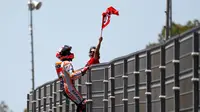 Pembalap Repsol Honda, Marc Marquez memanjat pagar lintasan setelah berhasil finis pertama pada balapan MotoGP Spanyol 2018 di Sirkuit Jerez, Minggu (6/5). Marquez mengukir waktu 41 menit 39,678 detik. (AP Photo/Miguel Morenatti)