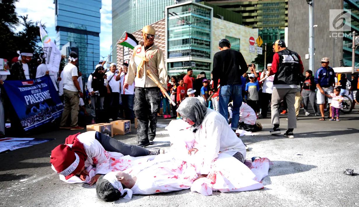 Peserta aksi melakukan teatrikal tentang kekejaman tentara Israel di kawasan Bundaran HI, Jakarta, Minggu (10/12). Selain itu, mereka juga melakukan aksi penggalangan tanda tangan dan dukungan bagi negara Palestina. (Liputan6.com/Helmi Fithriansyah)