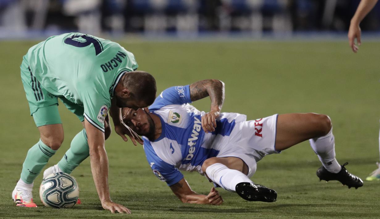 Pemain Real Madrid Nacho (kiri) berebut bola dengan pemain Leganes Miguel Angel Guerrero pada pertandingan La Liga di Stadion Butarque, Leganes, Madrid, Spanyol, Minggu (19/7/2020). Pertandingan berakhir dengan skor 2-2. (AP Photo/Bernat Armangue)