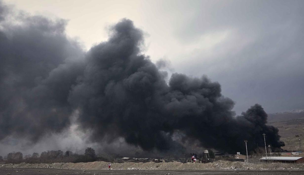 Tim pemadam kebakaran dan darurat Iran terus berjibaku memadamkan kobaran api akibat serangan tersebut. Tampak dalam foto, kepulan asap tebal membubung dari fasilitas penyimpanan minyak yang terkena serangan AS-Israel pada Sabtu 7 Maret 2026 malam di Teheran, Iran, Minggu 8 Maret 2026. (AP Photo/Vahid Salemi)