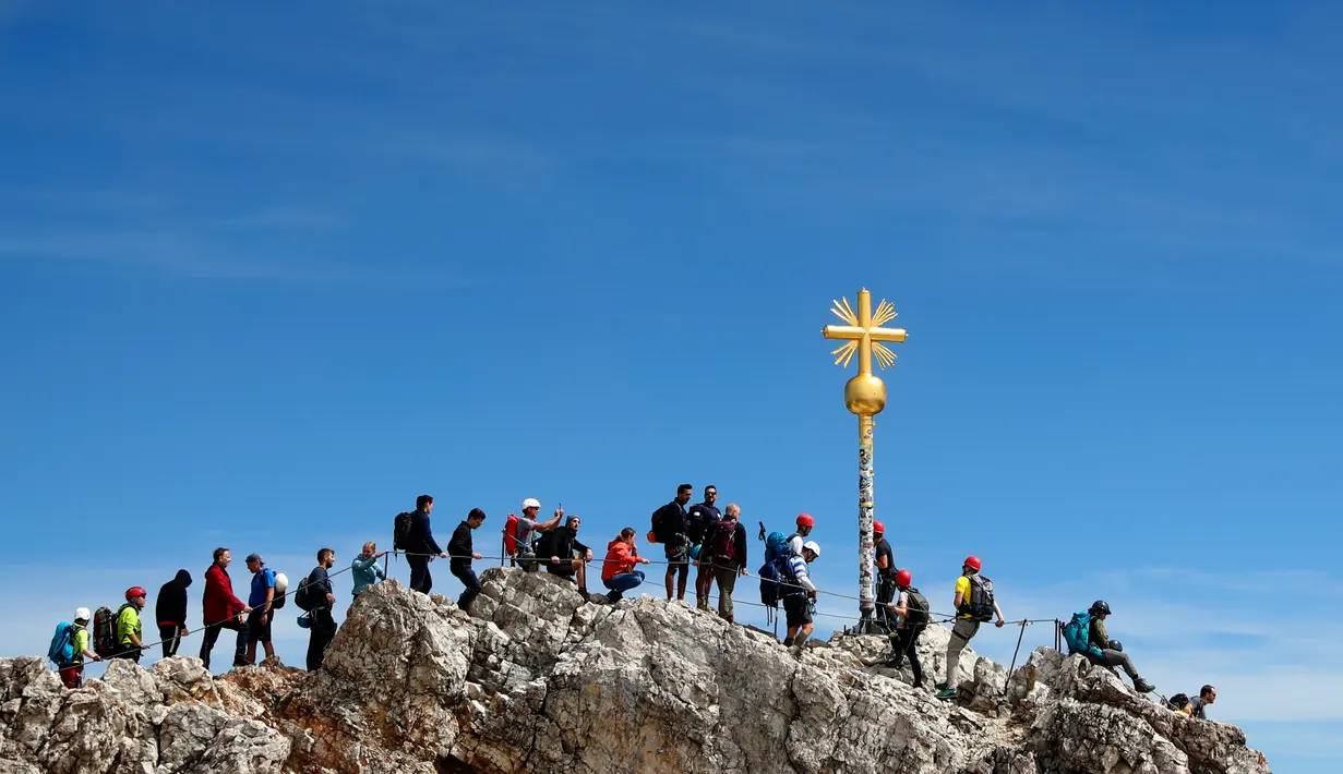 Orang-orang mengantre untuk mencapai puncak salib di puncak gunung tertinggi Jerman, Zugspitze, dekat Garmisch-Partenkirchen, Jerman pada 19 Agustus 2020. Setiap tahunnya gunung dengan ketinggian 2.962 meter tersebut membuat sekitar setengah juta pengunjung terpesona. (AP Photo/Matthias Schrader)