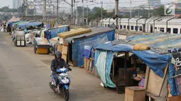 Pengedara melintas di depan gubuk liar yang berdiri di sepanjang jalur inspeksi Kanal Banjir Barat di Tanah Abang, Jakarta, Jumat (3/11). Kurangnya pengawasan menyebabkan daerah tersebut kembali dipenuhi gubuk liar. (Liputan6.com/Immanuel Antonius)