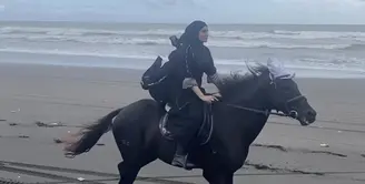 Zaskia Sungkar tampil memesona di atas kudu saat berada di pinggir pantai. Ia tampil dengan abaya hitam yang serasi dengan kerudungnya. (@zaskiasungkar15)