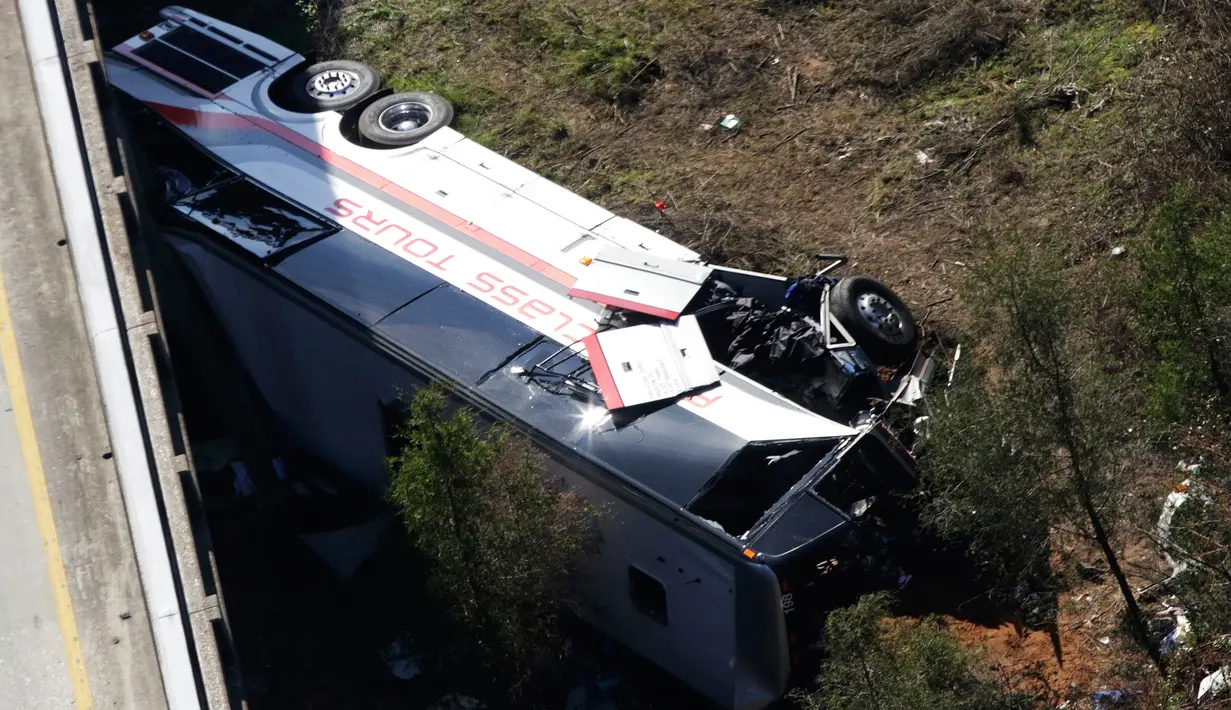 Sebuah bus carteran jatuh usai menabrak pembatas akibat kecelakaan di Loxley, Alabama (13/3). Bus tersebut membawa anggota band SMA di Texas pulang dari Disney World. (AP Photo / Dan Anderson)