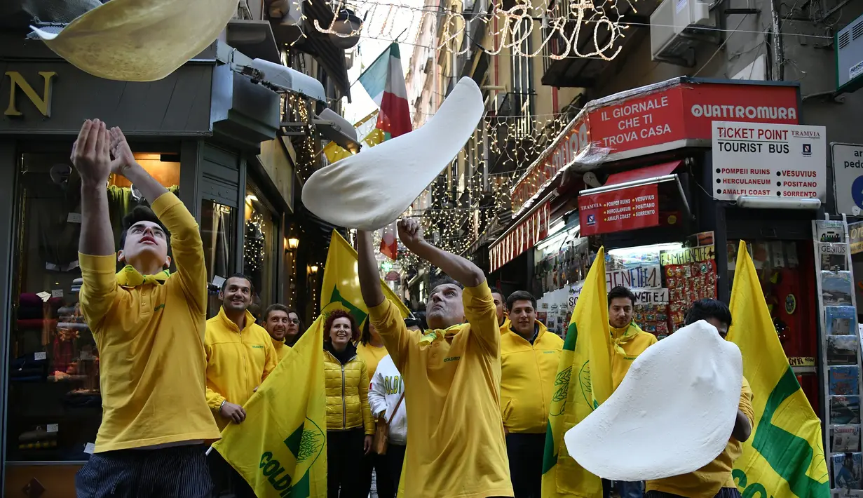 Anggota Pizzaioli Acrobats Coldiretti menunjukkan Pizzaioli untuk merayakan keputusan UNESCO di Naples, Italia, 7 Desember 2017. Pizzaioli adalah seni memutar adonan piza hingga mengembang dengan sempurna saat dipanggang. (Tiziana FABI/AFP)