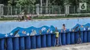 Anak-anak bersepeda di dekat seniman yang tengah menyelesaikan pembuatan mural di turap Kanal Banjir Barat, Jakarta, Rabu (13/1/2021). Pembuatan mural ini bertemakan "Kehidupan Sungai" ini dikerjakan oleh seniman dari Komunitas Mural Depok. (merdeka.com/Iqbal S. Nugroho)