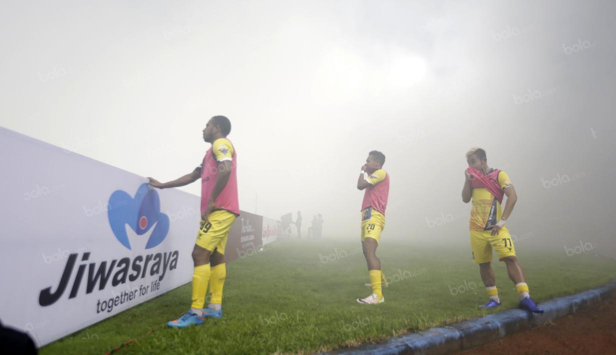 Oktovianus Maniani (kiri) dan dua rekannya dari pemain Persiba Balikpapan  hanya melihat kepulan asap flare saat melakukan pemanasan pada lagaTorabika SC 2016 di Stadion Gelora Bangkalan, Senin(13/6/2016).  (Bola.com/Nicklas Hanoatubun)