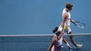 Petenis Rumania, Simona Halep (atas) dan Garbine Muguruza dari Spanyol meninggalkan lapangan setelah pertandingan semifinal tunggal putri Australia Terbuka di Melbourne, Australia, Kamis (30/1/2020). Halep gagal ke final Australia Terbuka 2020 usai kalah dari Muguruza 7-6, 7-5. (DAVID GREY/AFP)