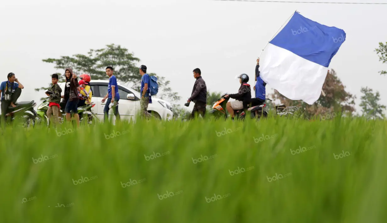 Belasan bobotoh berjalan melintasi sawah menyaksikan tim kesayangan Persib berlaga di Stadion Si Jalak Harupat, Soreang, Bandung, Rabu (30/3/2016). Perjuangan terbayar sukses Persib melaju ke final Torabika Bhayangkara Cup. (Bola.com/Nicklas Hanoatubun)
