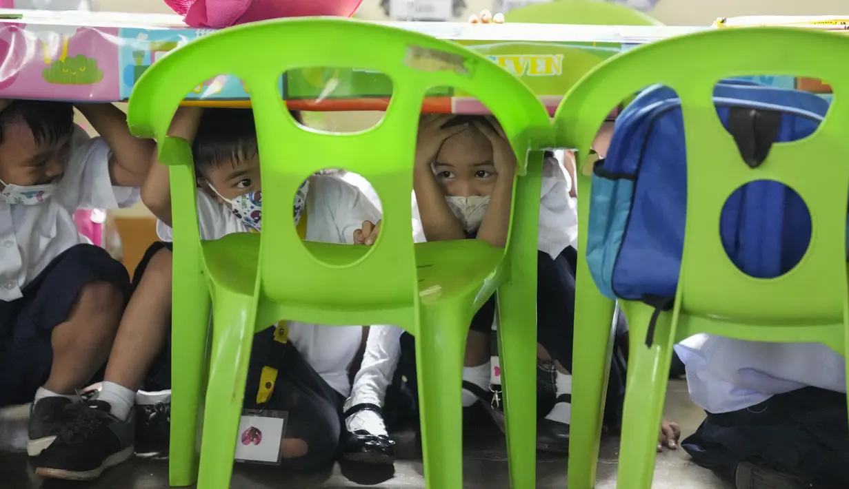 <p>Siswa menunduk di bawah meja selama latihan gempa di sebuah sekolah dasar di Metro Manila, Filipina, Kamis (8/9/2022). Filipina melakukan latihan gempa nasional kuartal ketiga sebagai bagian dari upaya untuk membuat publik mengetahui protokol dan tanggapan selama bencana. (AP Photo/Aaron Favila)</p>